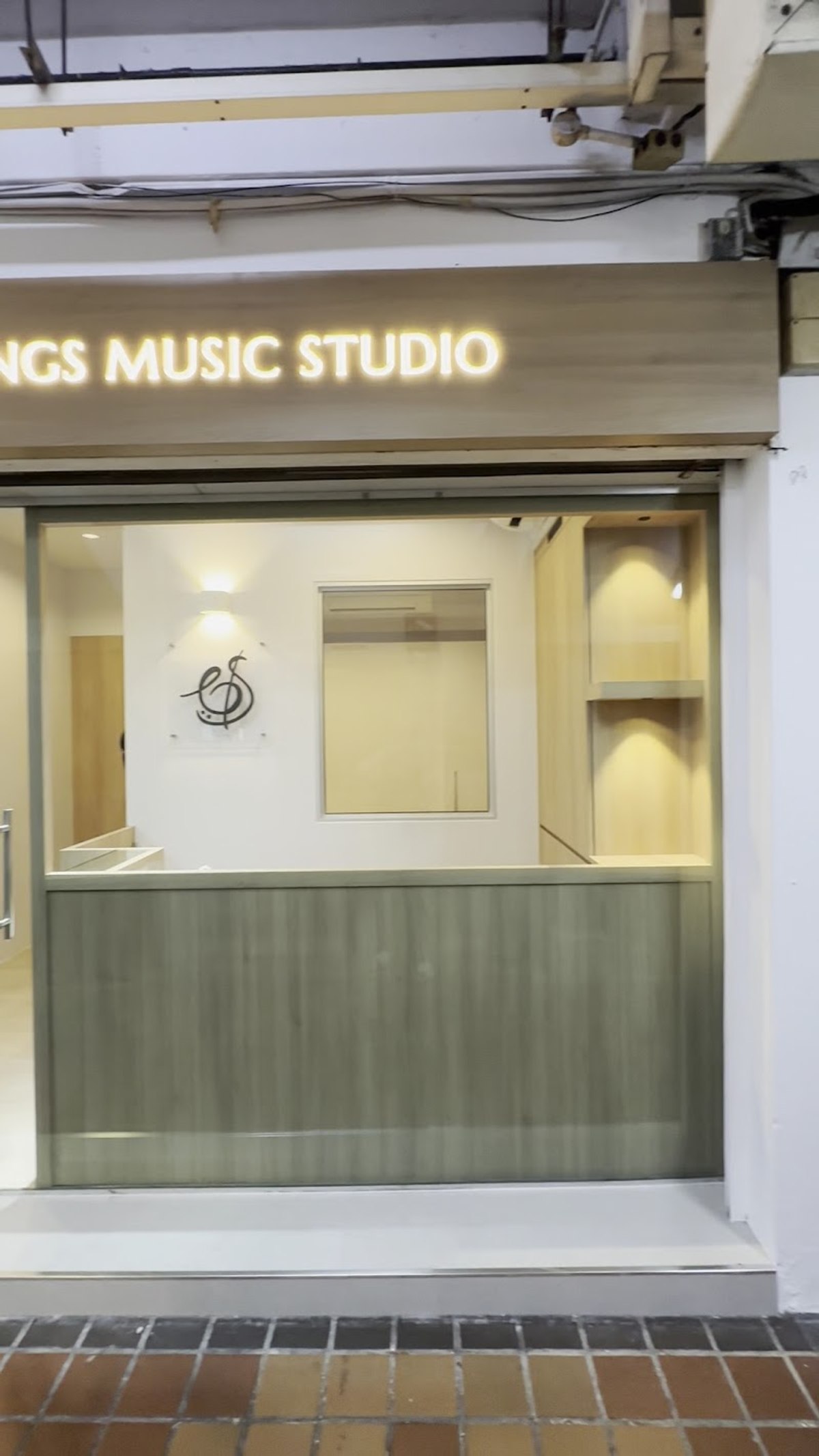 The Bowed Strings Music Studio storefront, its sign lit above the glass front
